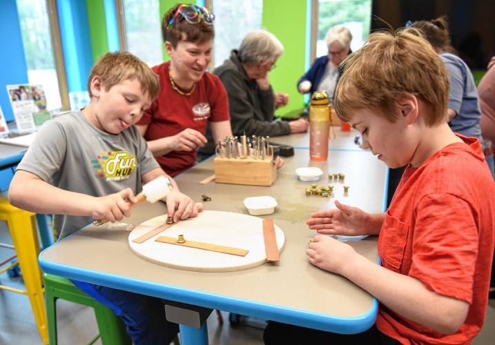 Erving resident Dalton Towne, 8, left, hammers a pattern into a leather strip as Cate Avery-Jagla and her son Abraham Jagla, 10, also of Erving, pick out their next dye as they tool leather at a workshop sponsored by the Erving Public Library and LaunchSpace on Wednesday at the library.