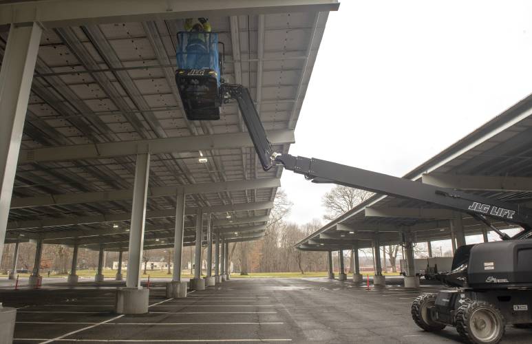 An employee with Massachusetts Electric works on finishing touches on the canopy solar parking lot off University Drive at UMass in December 2021.