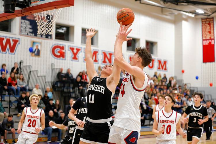 Frontier’s Owen Babb (14) drives to the hoop over Pioneer defender Hugh Cyhowski (11) in the second quarter Friday night at Goodnow Gymnasium in South Deerfield.