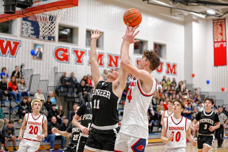 Frontier’s Owen Babb (14) drives to the hoop over Pioneer defender Hugh Cyhowski (11) in the second quarter Friday night at Goodnow Gymnasium in South Deerfield.